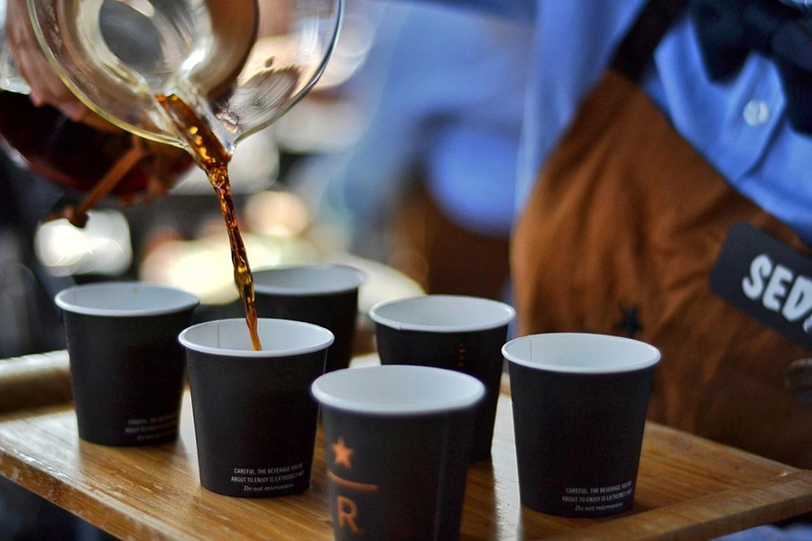 یک باریستا در حال سرو چای در لیوان های یکبار مصرف